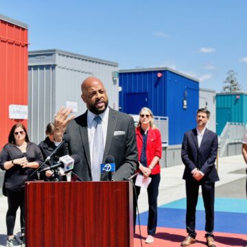 Aubrey Merriman LifeMoves A man speaking at a podium outside, with other people standing behind him