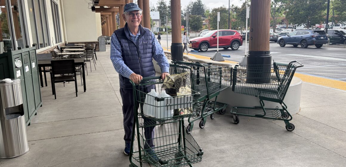 A man pushing a shopping cart of groceries