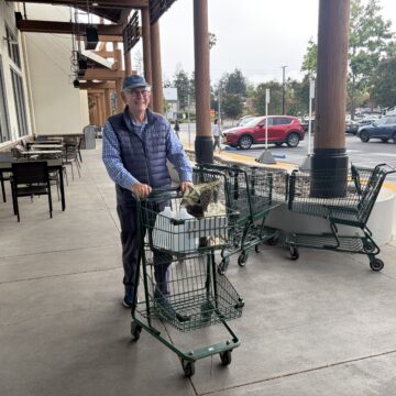 A man pushing a shopping cart of groceries