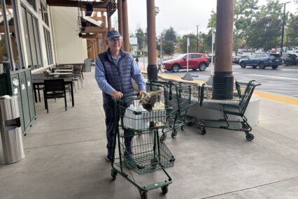A man pushing a shopping cart of groceries