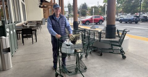 A man pushing a shopping cart of groceries