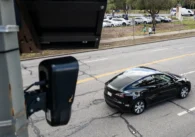 An automated license plate reader on a pole overlooking a car driving in Palo Alto, California