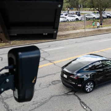 An automated license plate reader on a pole overlooking a car driving in Palo Alto, California