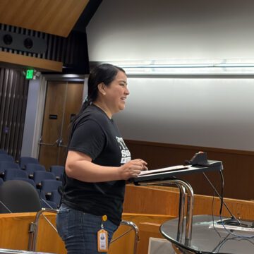 A woman standing at a podium at a government meeting