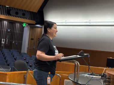 PROMOTORES A woman standing at a podium at a government meeting