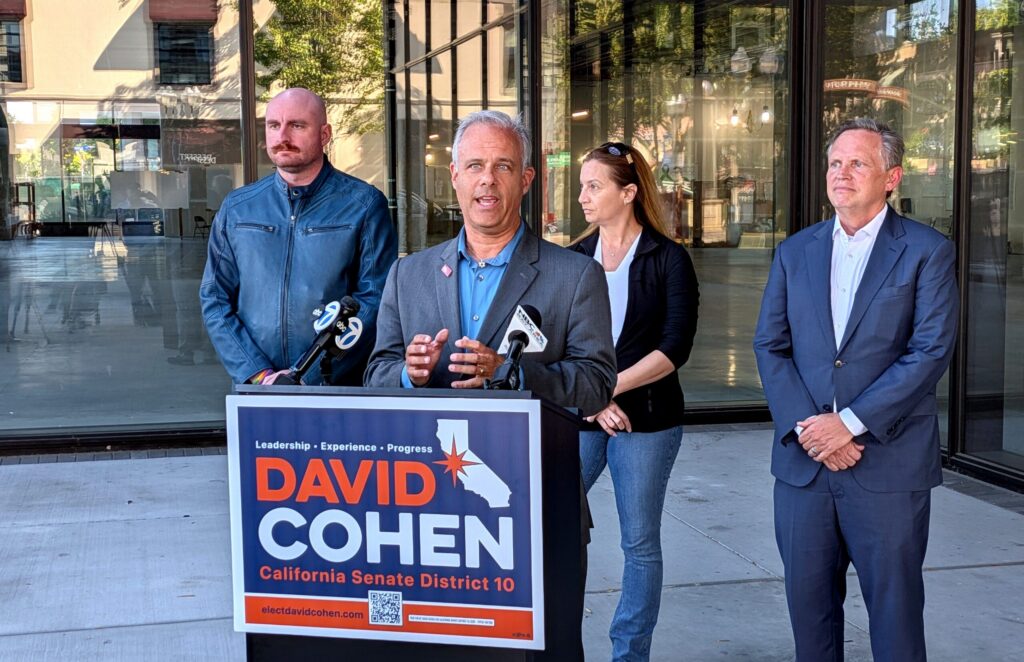 A man speaks at a podium outside