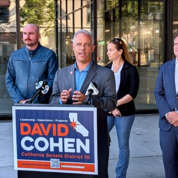 David Cohen presser A man speaks at a podium outside