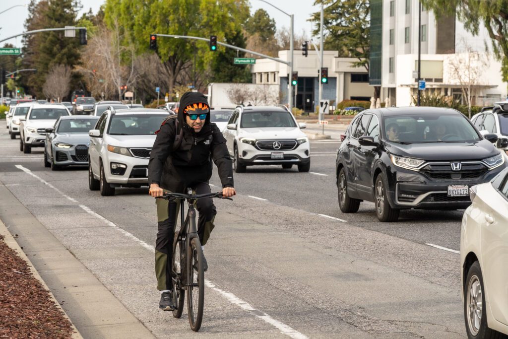A man rides a bike along cars in Mountain View, California