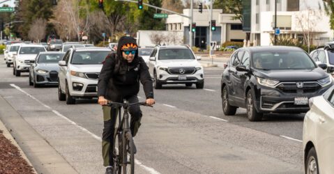 A man rides a bike along cars in Mountain View, California