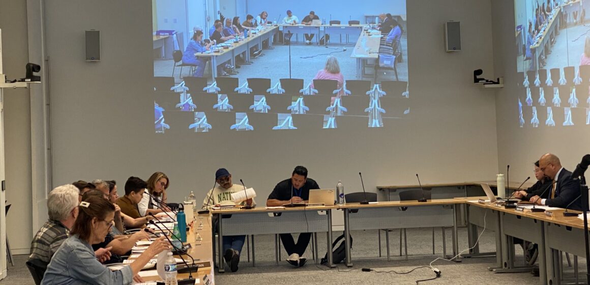 People sit at tables in a government meeting in San Jose, California