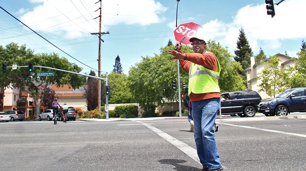 A crossing guard holds a stop sign in the street in Palo Alto, California