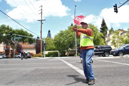 A crossing guard holds a stop sign in the street in Palo Alto, California