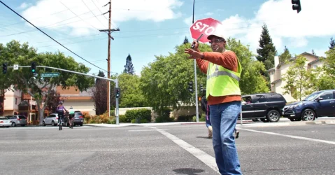 A crossing guard holds a stop sign in the street in Palo Alto, California