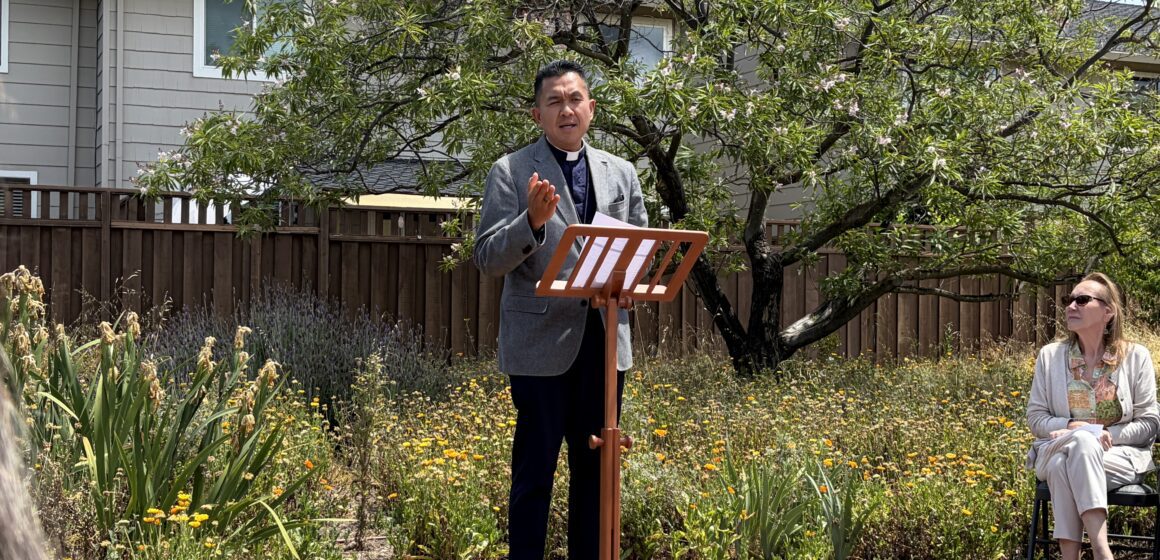 A man stands at a podium outside leading a prayer