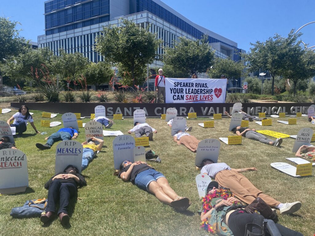 Personas tumbadas en un césped junto a lápidas falsas en San José, California.