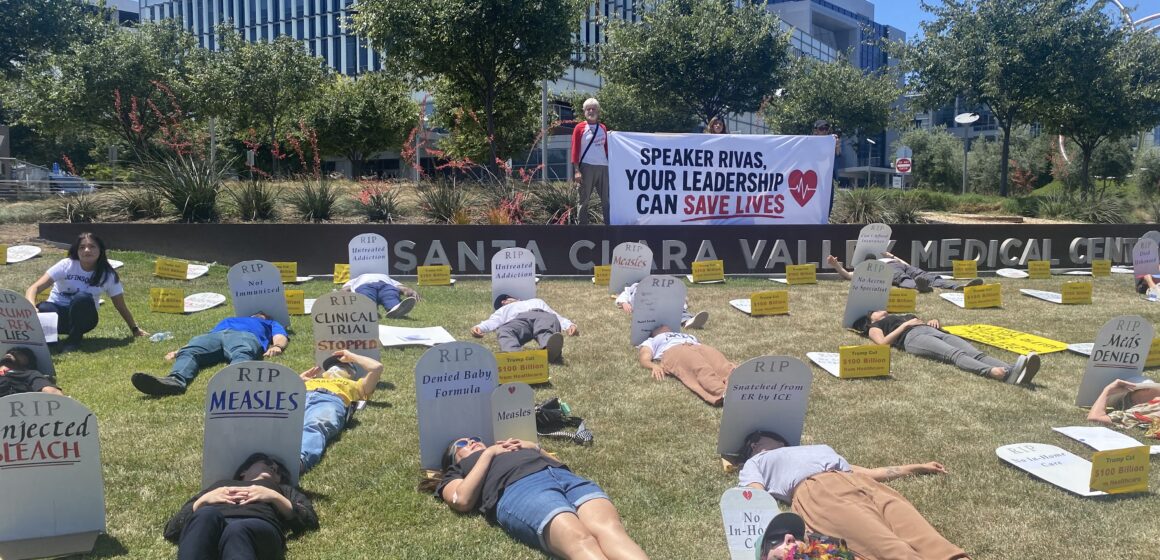 People lying down on a lawn next to fake tombstones in San Jose, California