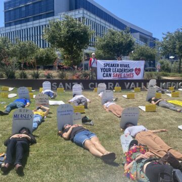 People lying down on a lawn next to fake tombstones in San Jose, California
