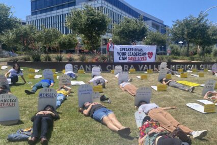 People lying down on a lawn next to fake tombstones in San Jose, California