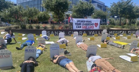 People lying down on a lawn next to fake tombstones in San Jose, California
