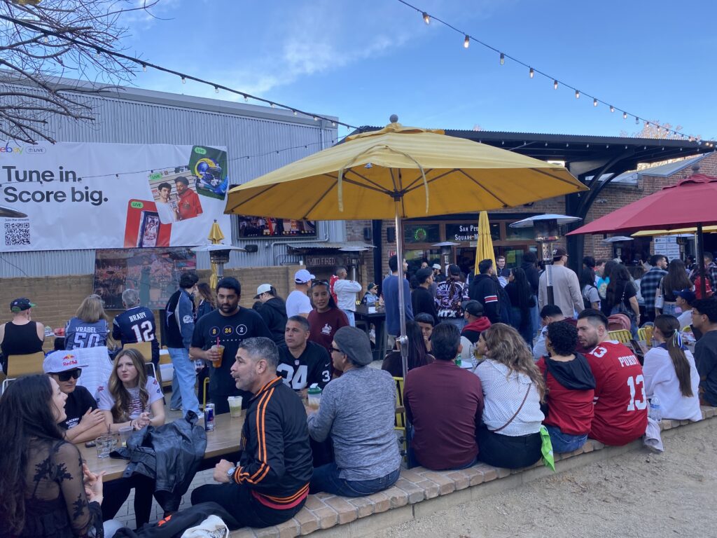 People sit underneath a yellow umbrella in an outdoor patio
