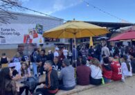 People sit underneath a yellow umbrella in an outdoor patio
