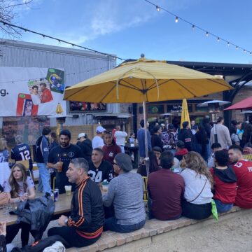 Super Bowl 60 watch party People sit underneath a yellow umbrella in an outdoor patio