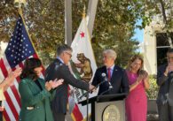 Two men shaking hands at a podium at a government press conference in San Jose, California