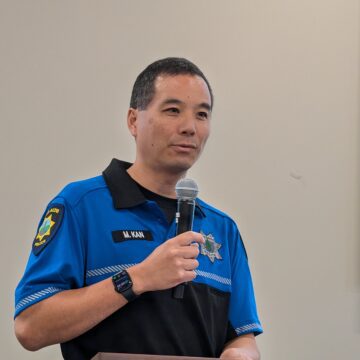 A man in a police uniform speaking into a microphone