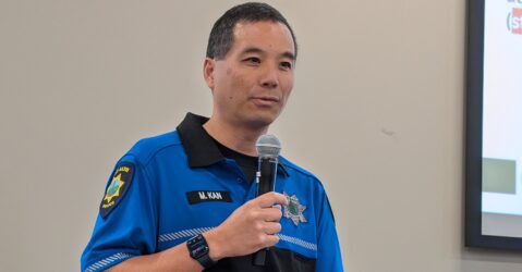 A man in a police uniform speaking into a microphone