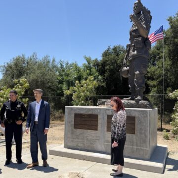People gather around the feat of a memorial.