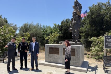 People gather around the feat of a memorial.