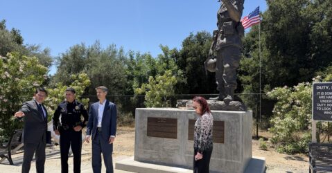 People gather around the feat of a memorial.