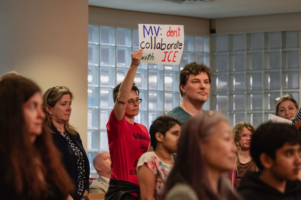 People at meeting holding up signs