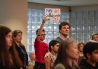 People at meeting holding up signs