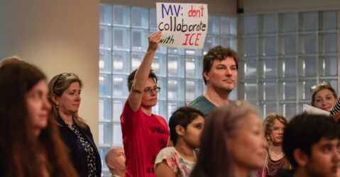 People at meeting holding up signs