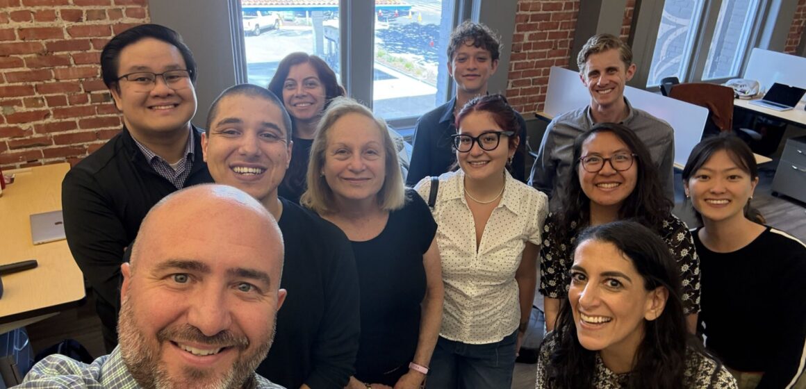 A group of people in an office posing for a selfie photo