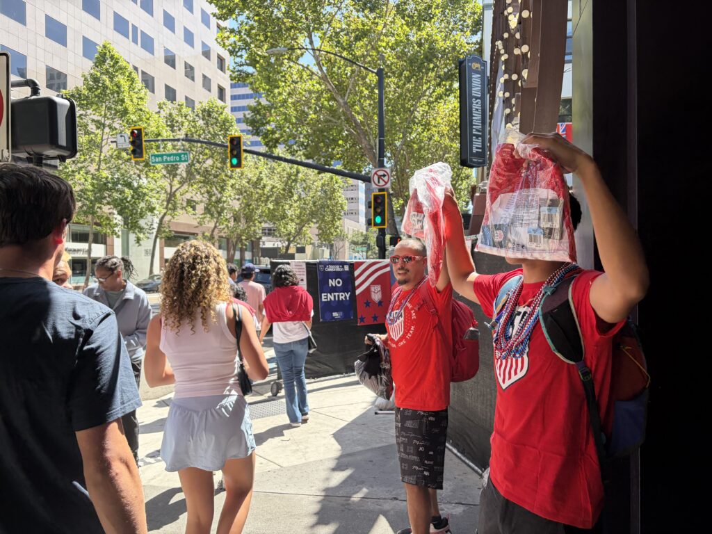 Two men selling soccer jerseys as people walk by in downtown San Jose, California