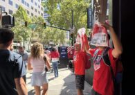 Two men selling soccer jerseys as people walk by in downtown San Jose, California