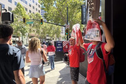 Two men selling soccer jerseys as people walk by in downtown San Jose, California