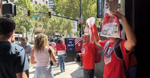 Two men selling soccer jerseys as people walk by in downtown San Jose, California
