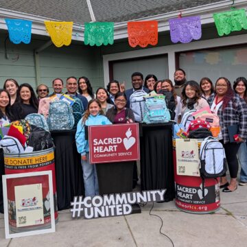 A group of people standing with backpacks full of school supplies to give to students in need