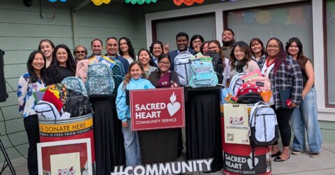 A group of people standing with backpacks full of school supplies to give to students in need