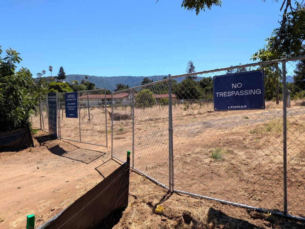 A chain link fence with a dirt road behind it in Saratoga, California