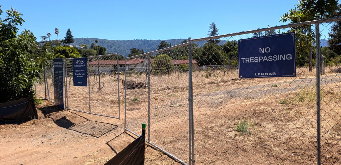 Saratoga vineyard site A chain link fence with a dirt road behind it in Saratoga, California