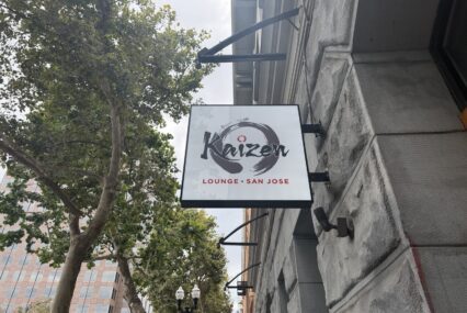A sign on a stone building next to trees.