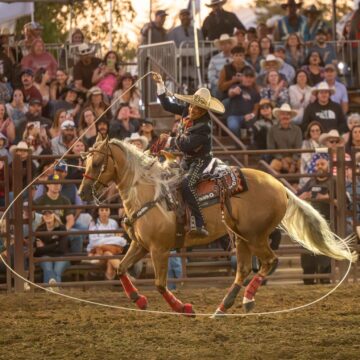 Una persona montada a caballo hace girar un lazo en un rodeo en Gilroy, California.