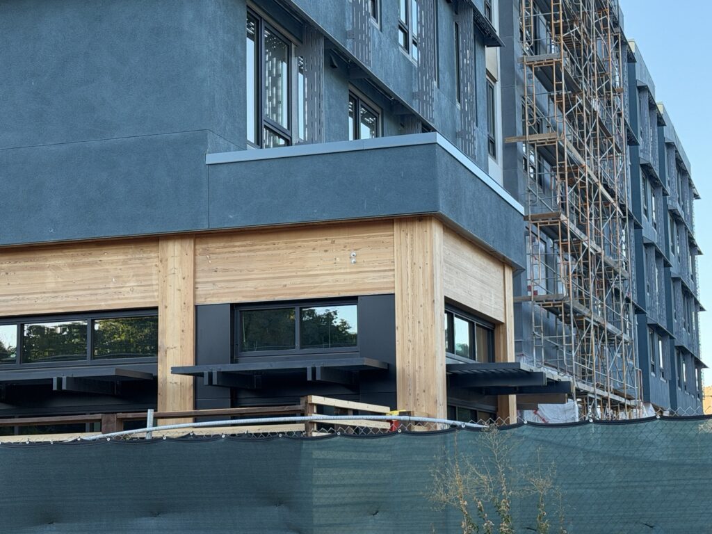 A blue building standing on a wooden base behind a fence.
