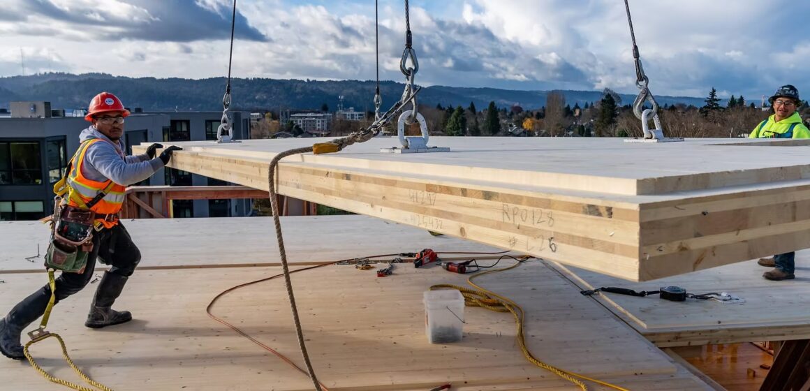 Mass timber Construction workers handling mass timber being lifted by a crane