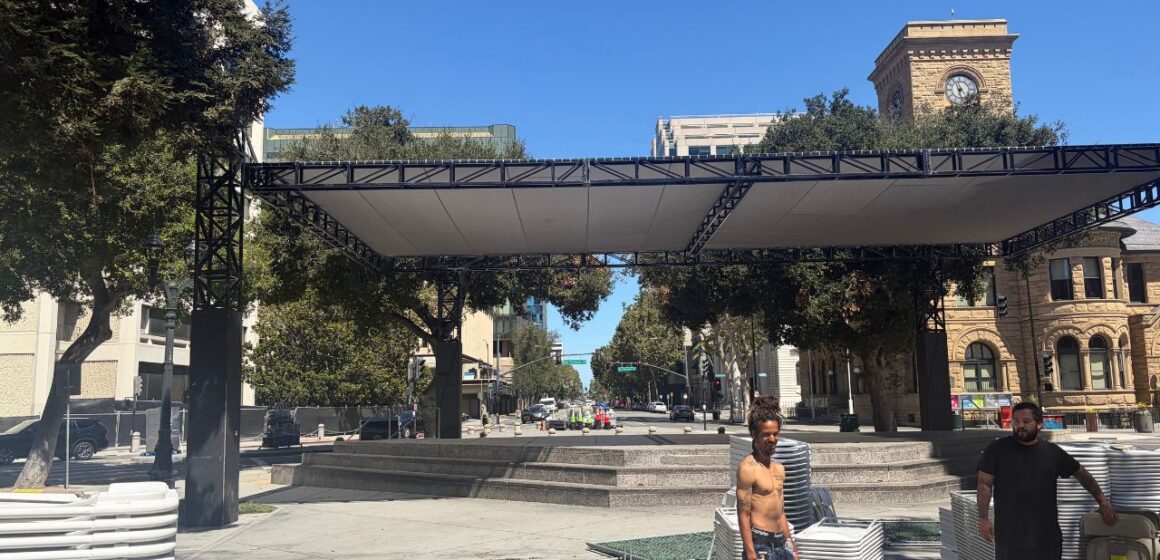 Two men standing in a plaza with stacks of plastic chairs in San Jose, California