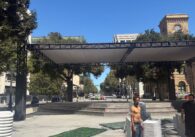 Two men standing in a plaza with stacks of plastic chairs in San Jose, California